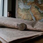 Een fysieke bitcoin-munt op een financiële krant met een wereldkaart van het Midden-Oosten op de achtergrond