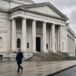 Anonieme man loopt langs de zuilengalerij van het gebouw van de Amerikaanse centrale bank op een grijze dag
