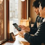 Klant betaalt met smartphone aan de toonbank van een winkel in Tokio terwijl de verkoper een tas aangeeft