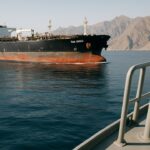 Een olietanker vaart door de smalle Straat van Hormuz met bergachtige kust op de achtergrond