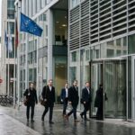 Modern glazen kantoorgebouw van een betaalbedrijf in een Europese zakenwijk met een EU-vlag ervoor