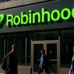 Buitengevel met een groot, helder verlicht Robinhood-logo aan een straat